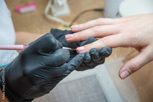a master does a manicure to a client in a beauty salon and covers her nails