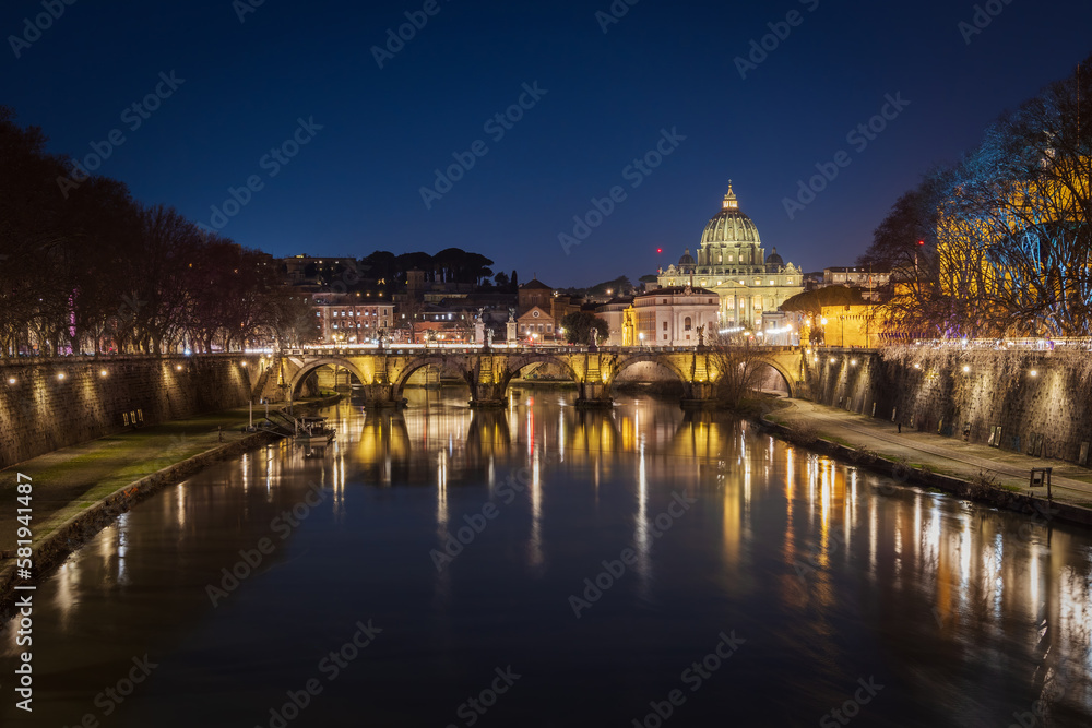 Cityscape with Sant Angelo bridge and St. Peter's cathedral at night with city lights in Rome, Italy