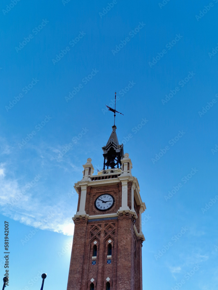An interesting, historic tower with a clock against the background of the blue sky on a sunny winter day, Madrid, Spain.
