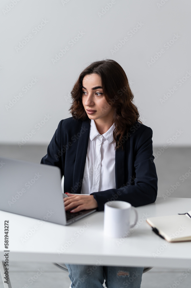 An attractive woman is sitting at a workplace and working on a laptop An attractive woman is sitting at a workplace and working on a laptop