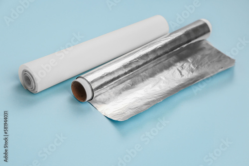 Rolls of aluminium foil and baking paper on blue background