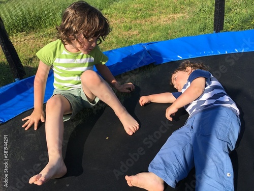 two curly brothers play and relax sit and lie on the trampoline