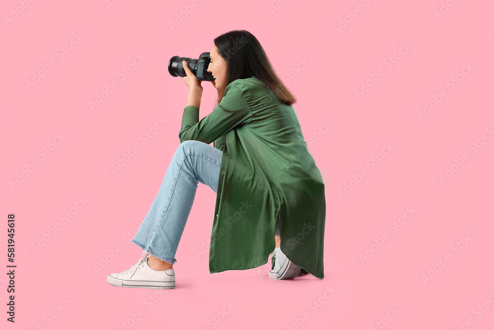 Obraz premium Female photographer with professional camera on pink background