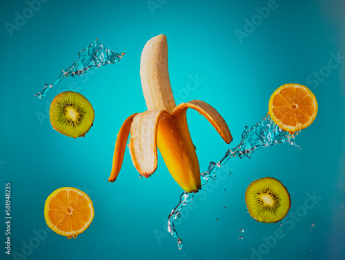 Fototapeta Naklejka Na Ścianę i Meble -  Fling fruit with water splashed over it, shot on a blue gradient background.