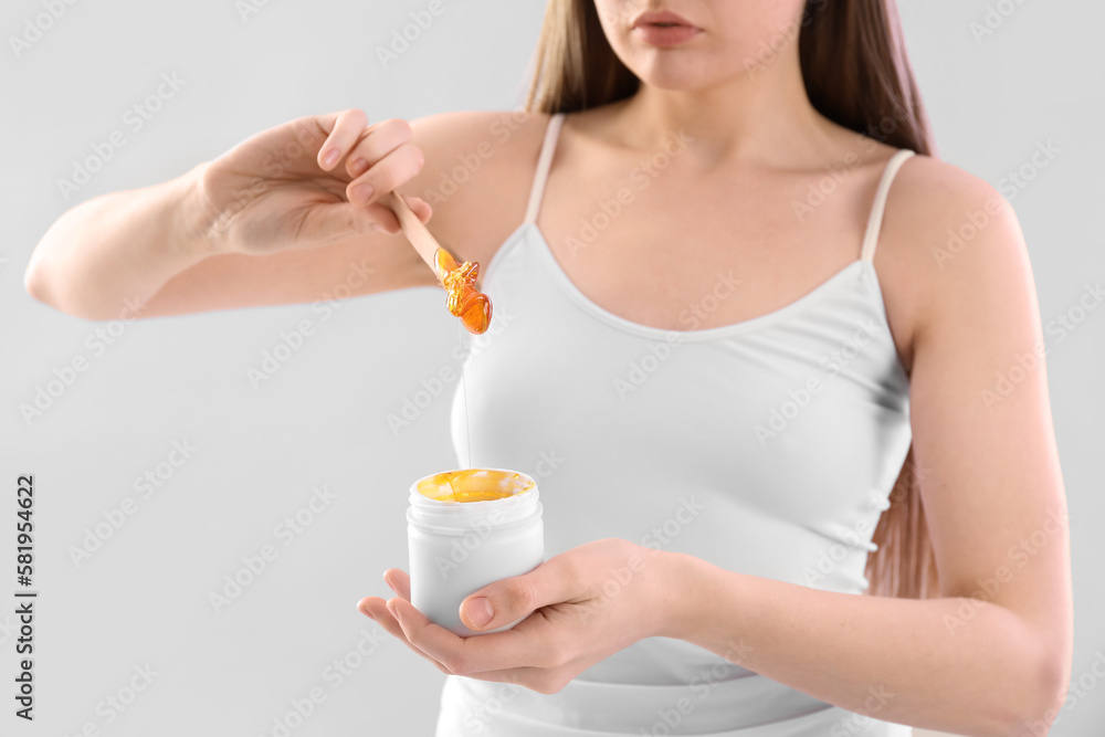 Young woman with sugaring paste on light background Young woman with sugaring paste on light background