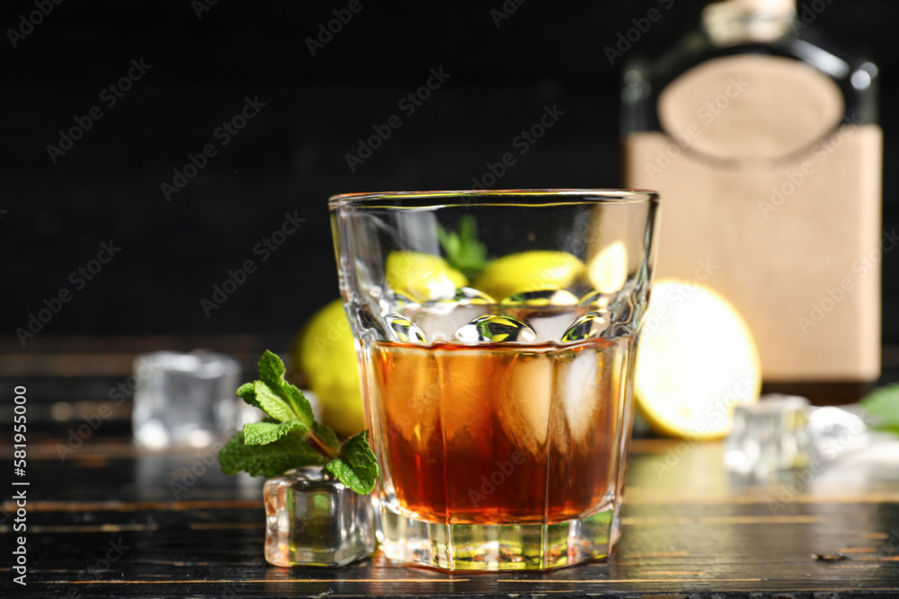Glass of rum with ice cubes on dark wooden background Glass of rum with ice cubes on dark wooden background