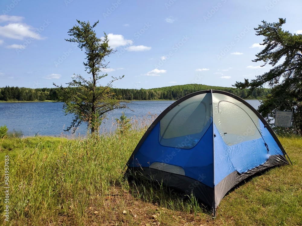 Camping tent in woods by lake