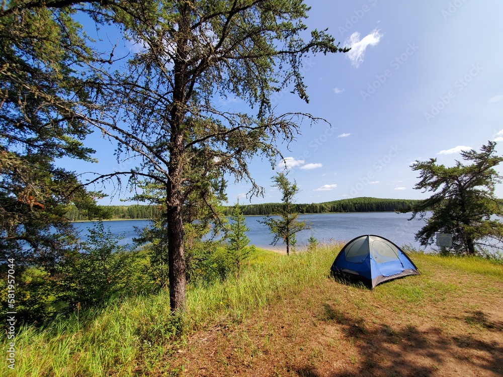Camping tent in woods by lake