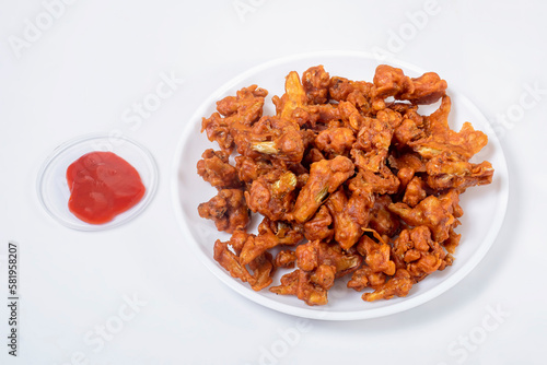 Crispy Fried Gobi Manchurian on white plate with ketchup on white background.