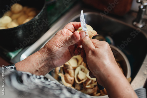 Close up of hands of a latin indigenous woman who is peeling potatoes in her kitchen sink