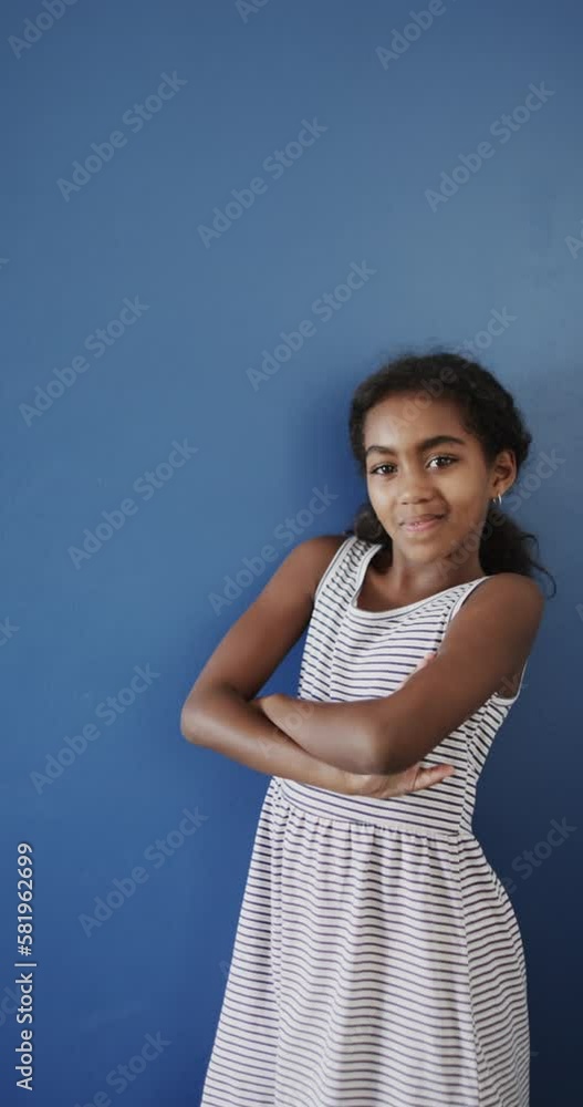 Vertical video of happy biracial girl smiling on blue background, slow motion Vertical video of happy biracial girl smiling on blue background, slow motion