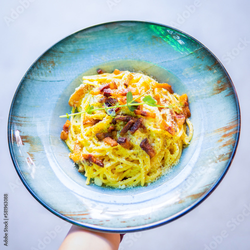 A bowl of pasta with is being held by a person.