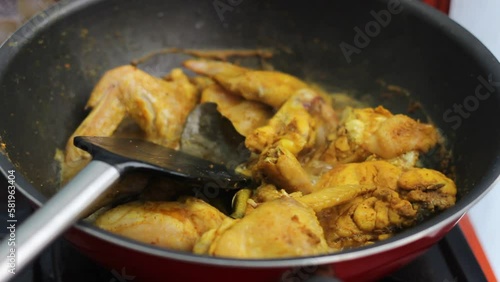 Chicken thighs seasoned with yellow sauce contains tumeric, garlic, shallot, ginger, galangal, pepper, and coriander. Chicken thighs is cooked in a stainless wok. Chicken (ungkep) from Indonesia.
 photo