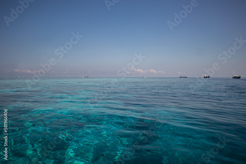 Boats on the horizon on blue calm ocean surface