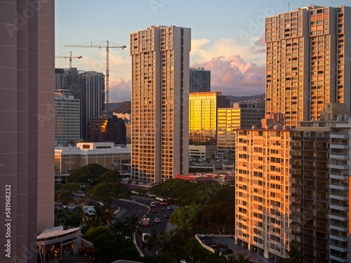 The high rise hotels of Honolulu's famous Waikiki neighborhood glow orange as the sun drops below the horizon