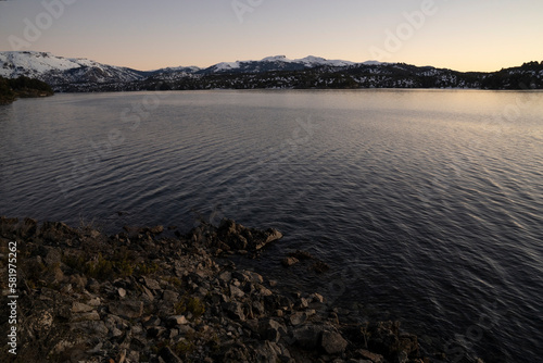 View of the lake and mountains at nightfall. Beautiful sunset colores in the water and sky.  