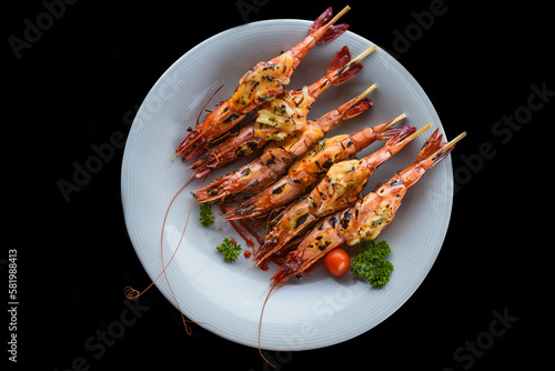 Grilled shrimps with cheese on blue plate isolated on black background top view