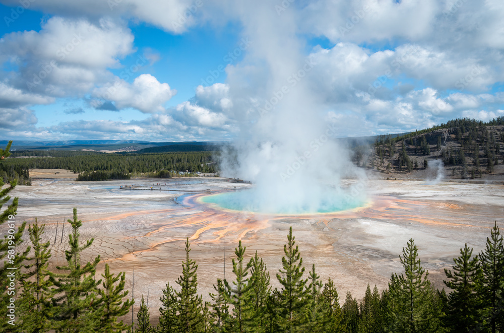 Steam rising from Grand Prismatic Hot Spring, indistinctive tourists walking on the boardwalk. Yellowstone National Park, United States.