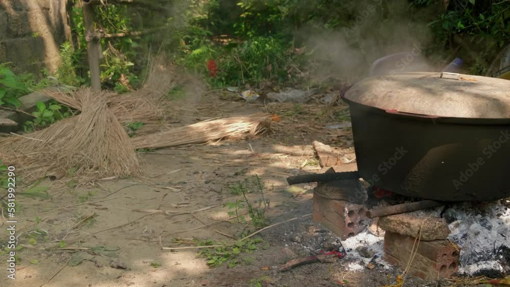 Large iron pot smoking on open fire pit with fresh straws on the floor Large iron pot smoking on open fire pit with fresh straws on the floor