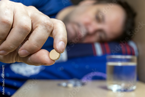 Photography A man lying in bed takes a pill