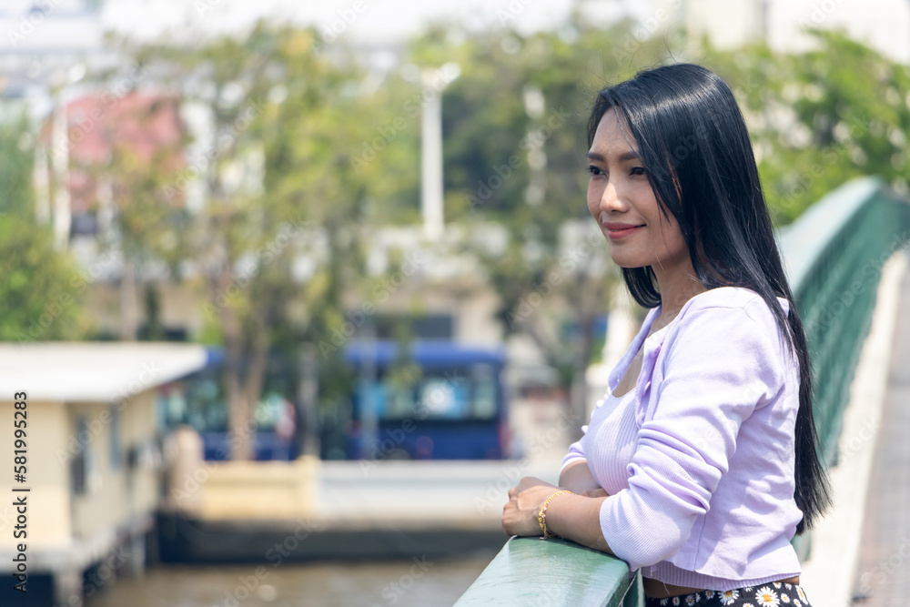 A young woman looks from the bridge over the Chao Phraya river in the center of Bangkok, Thailand A young woman looks from the bridge over the Chao Phraya river in the center of Bangkok, Thailand