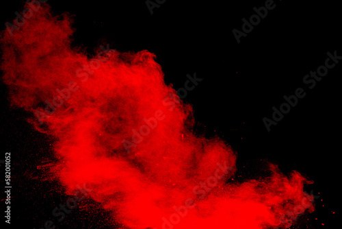 Red powder explosion cloud on black background. Freeze motion of red color dust particles splashing.