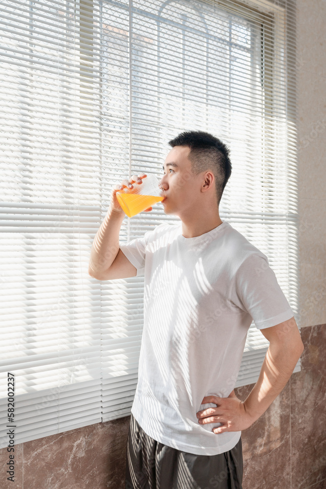 Fototapeta premium Asian man is drinking juice near the window in the morning.