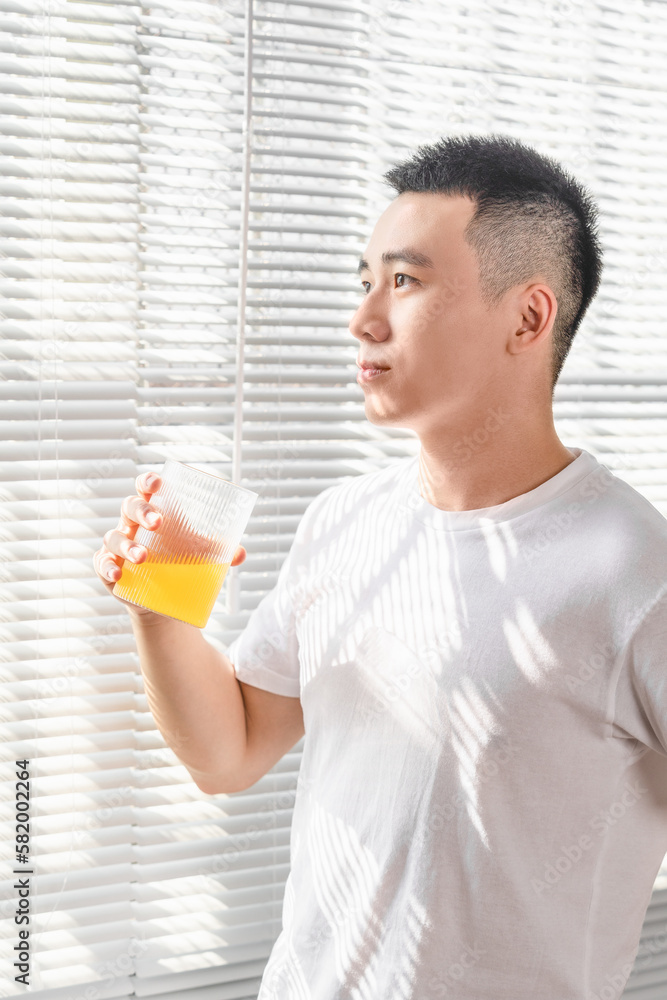 Asian man is drinking juice near the window in the morning. Asian man is drinking juice near the window in the morning.