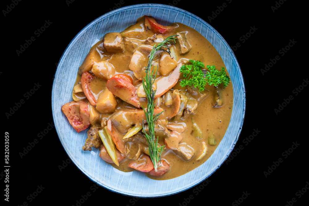 Stewed beef with vegetables on blue plate isolated on black background top view Stewed beef with vegetables on blue plate isolated on black background top view