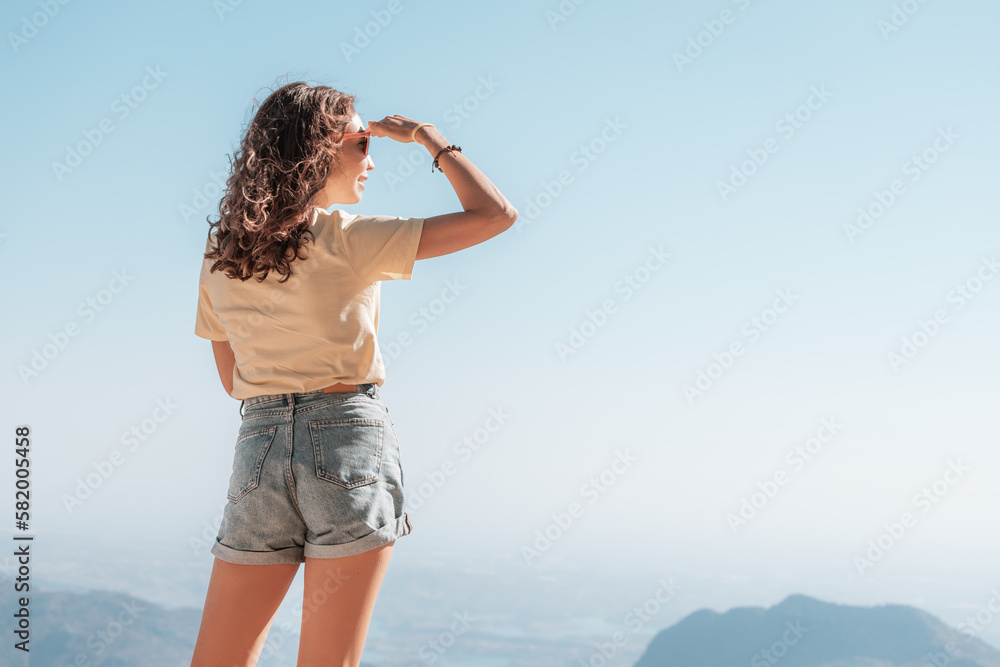 Obraz premium Girl wearing jeans shorts at scenic viewpoint with majestic panorama of mountain canyon
