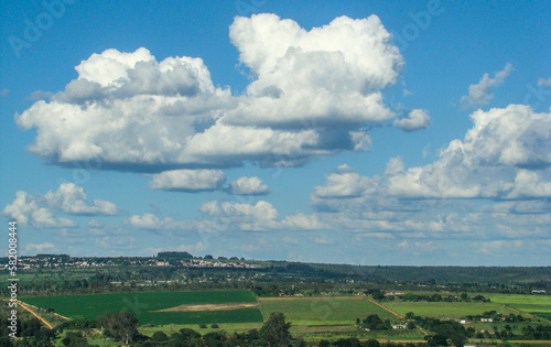 nature landscape with clouds and blue sky over the greenfield with the urban city on the horizon 