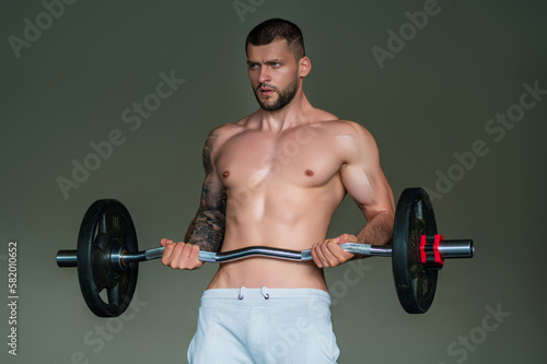Muscular hunk with posing in gym. Fitness male model near gym equipment. Young muscular man workout. Sport man with strong muscular torso in gym. Sport and motivation. Exercises with weight.
