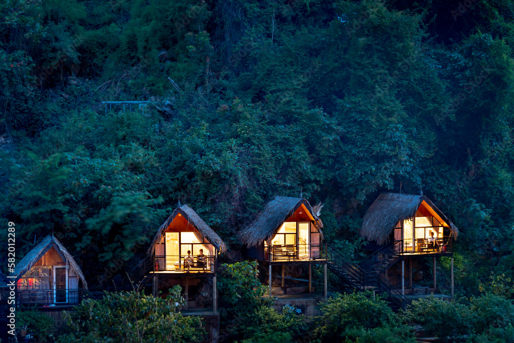 Three small wooden houses with lights in the tropical forest Three small wooden houses with lights in the tropical forest