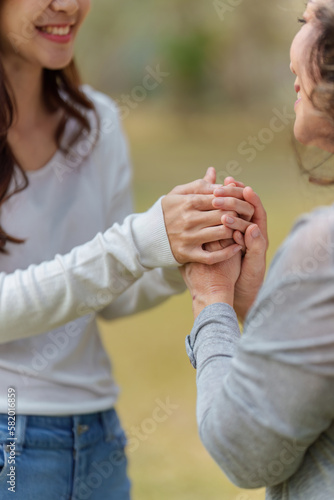 Close up of Adult daughter holding her elderly mother hand with love and walk together