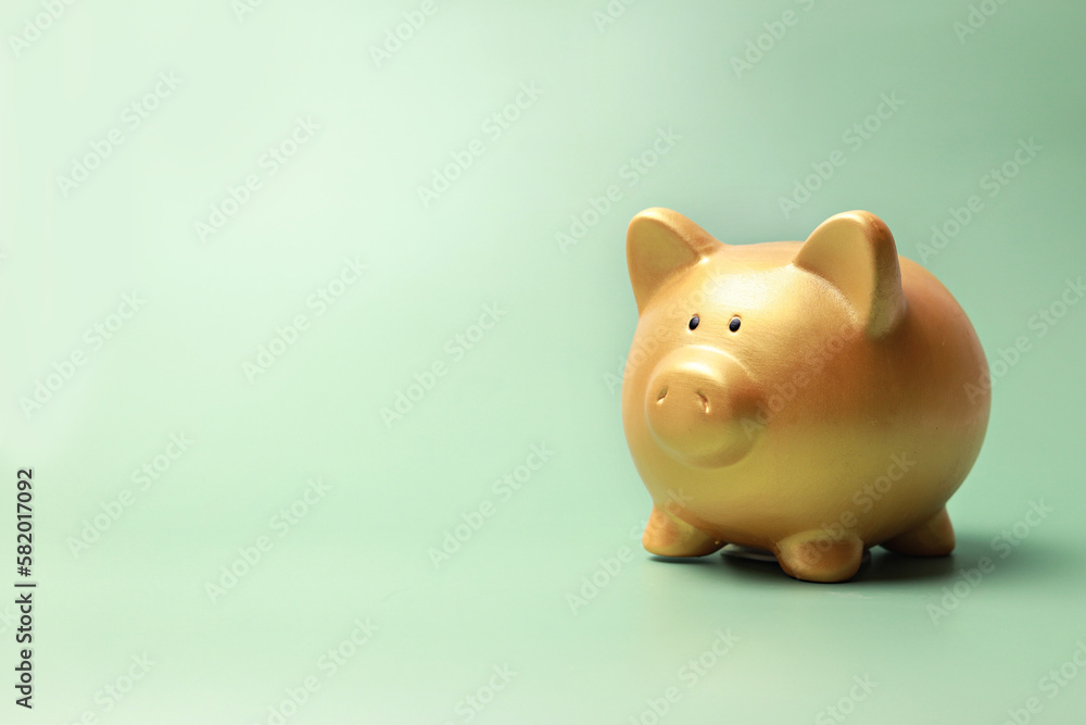Gold piggy bank on green background