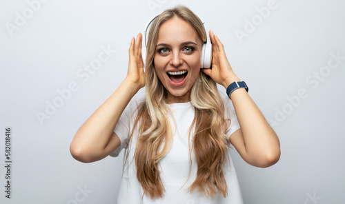 emotional young woman in white headphones listening to podcasts on white studio background