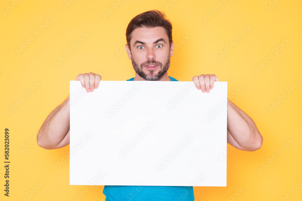 Surprised man holds the white sign, blank card. Placard ready for your product. Sign to your text. Amazed man showing blank sign board on studio background. Empty blank board. Area for advertising. Surprised man holds the white sign, blank card. Placard ready for your product. Sign to your text. Amazed man showing blank sign board on studio background. Empty blank board. Area for advertising.