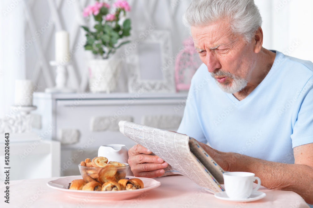 Emotional senior man reading newspaper at home Emotional senior man reading newspaper at home