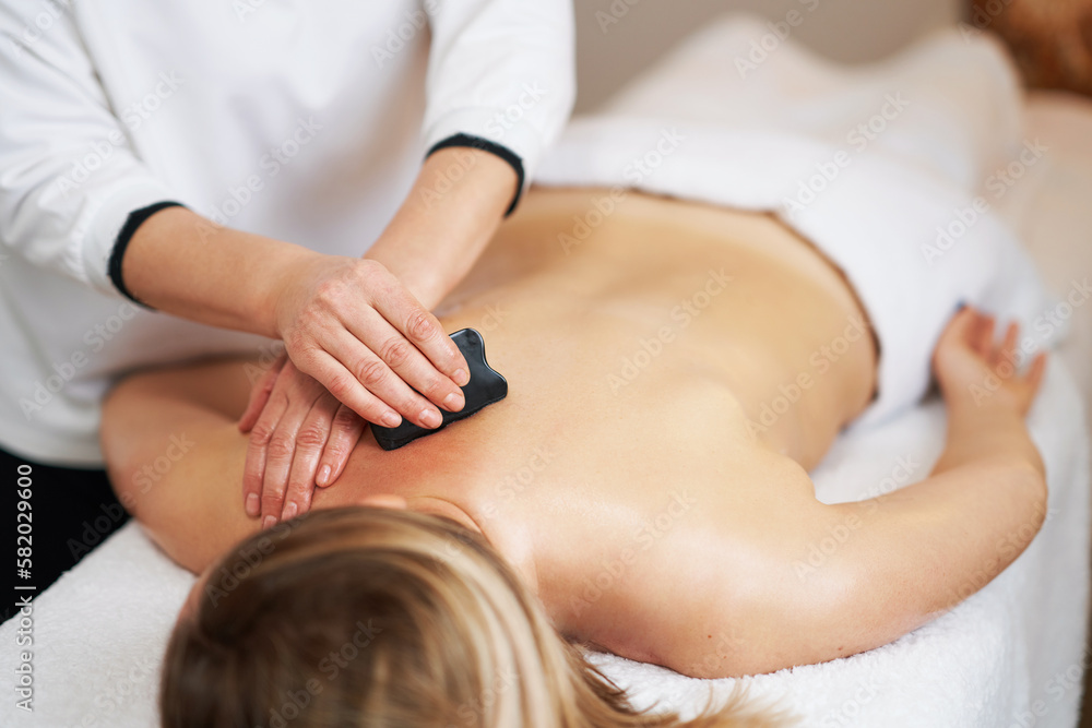 Woman having a gua sha massage in salon Woman having a gua sha massage in salon