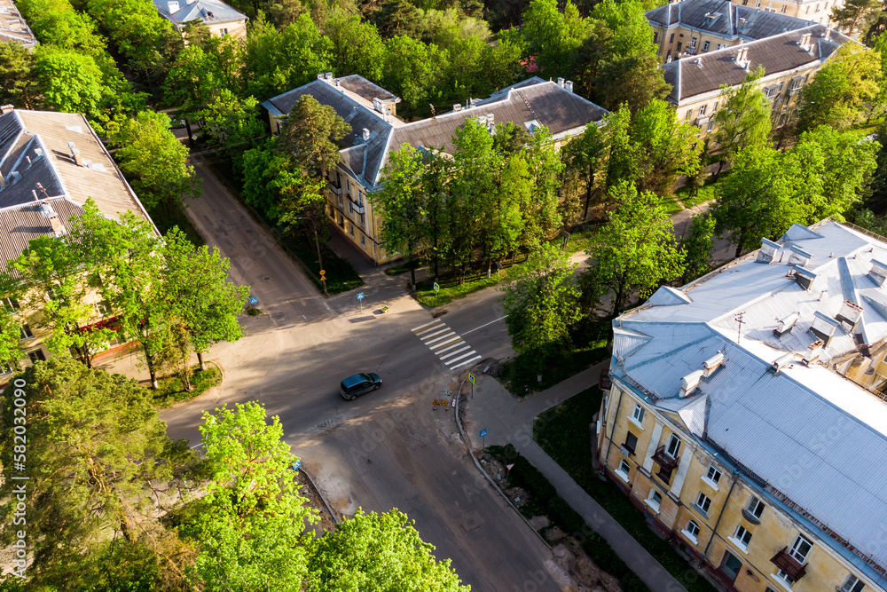 Aerial view of a highway intersection in a city surrounded by green trees Aerial view of a highway intersection in a city surrounded by green trees