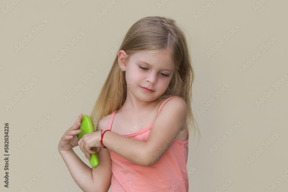 Candid portrait of cute little girl combing her long hair with detangler brush Candid portrait of cute little girl combing her long hair with detangler brush