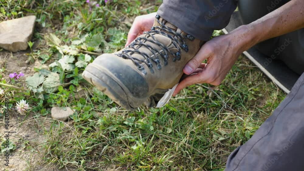 Closeup of a man's hands mending a torn leather walking boot. The sole