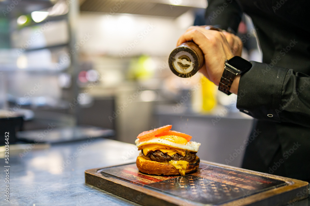 chef hand cooking cheeseburger with vegetables and egg on restaurant kitchen chef hand cooking cheeseburger with vegetables and egg on restaurant kitchen