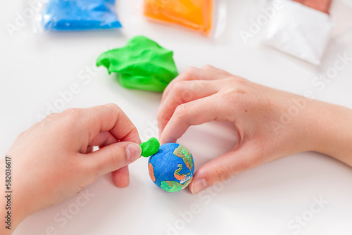Child's hands sculpt a model of the Earth from plasticine