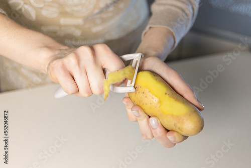 A girl is peeling potatoes in the kitchen