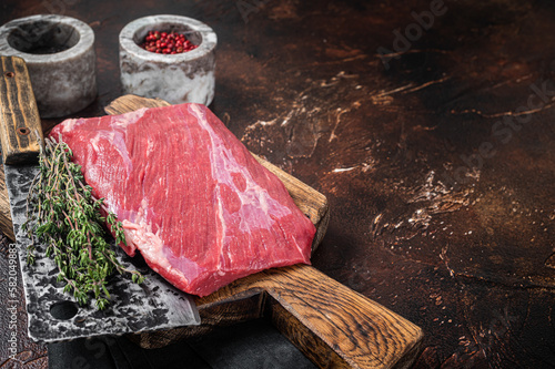 Alternative raw flap flank beef meat steak on butcher board. Dark background. Top view. Copy space photo