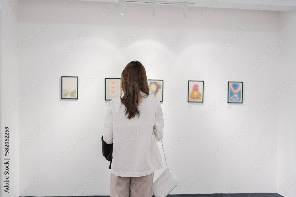 Woman visiting art gallery her looking pictures on wall watching photo frame painting at artwork museum people lifestyle concept.
