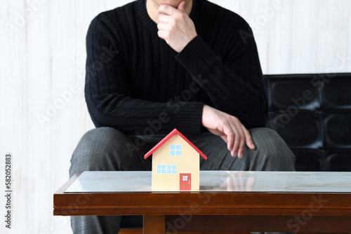 家づくり失敗イメージ―住宅の模型と悩む男性