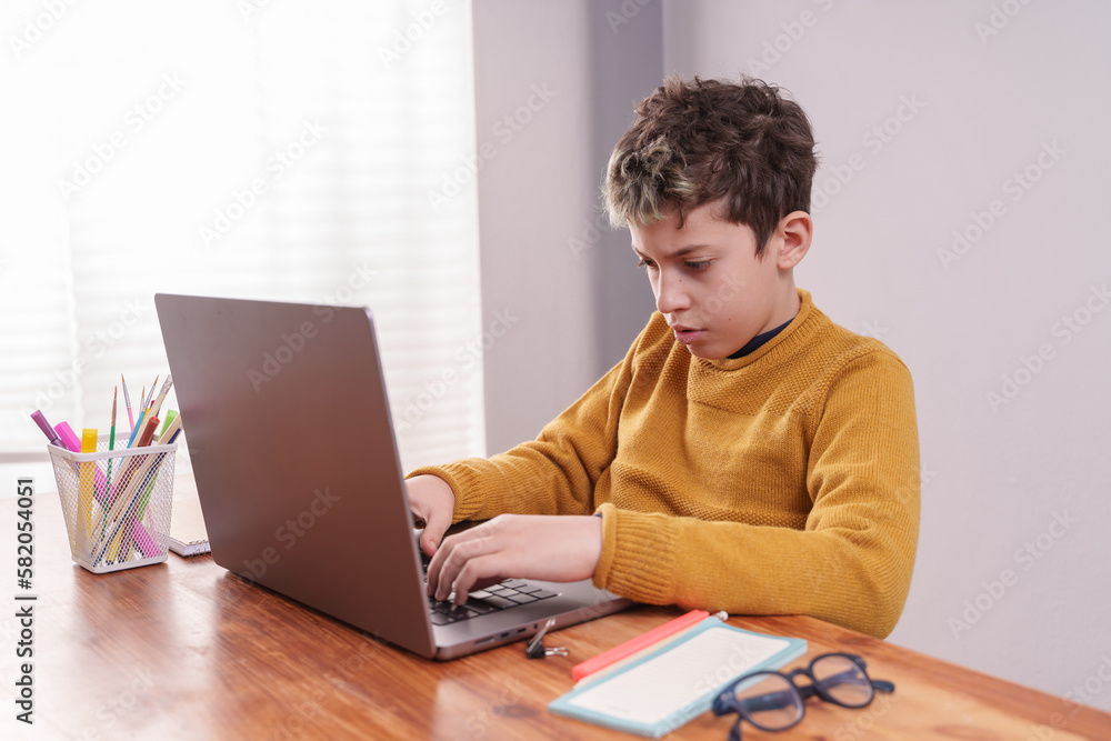 Focused child typing on laptop keyboard - Concentrated young boy typing on laptop Focused child typing on laptop keyboard - Concentrated young boy typing on laptop