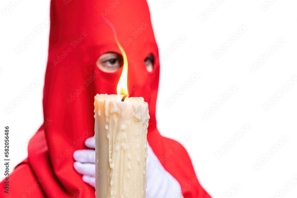 Φωτογραφία The candle in flame of a young Nazarene with a red hood doing his penance station in the Holy Week procession